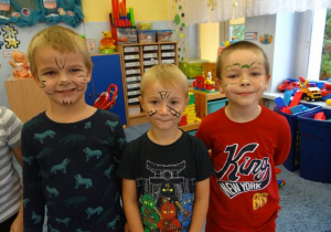 Trzech chłopców prezentuje pomalowane twarze